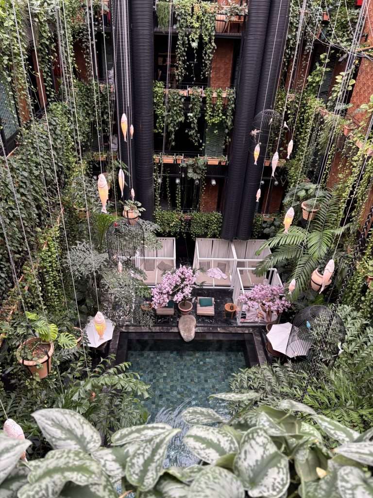 View of the lagoon-style pool at Manon Les Suites surrounded by hanging plants and soft lantern light, capturing a relaxing escape in Copenhagen in autumn.
