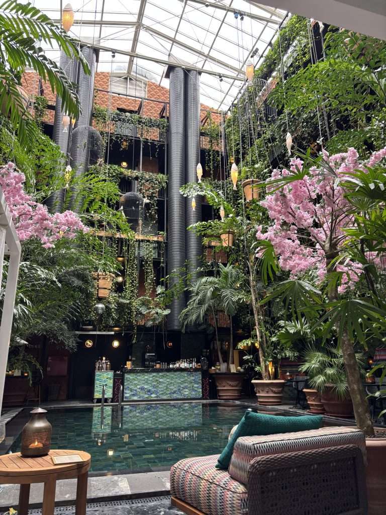 Overlooking the indoor courtyard pool at Manon Les Suites with guests relaxing under gentle lighting, creating hygge-inspired cosy vibes in Copenhagen in autumn.