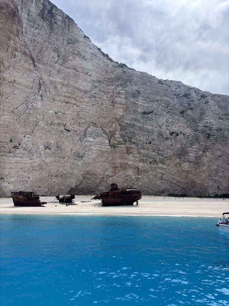approaching Shipwreck Beach in Zante by boat, with dramatic white cliffs surrounding the sandy cove and bright blue sea on a Zante shipwreck boat tour.