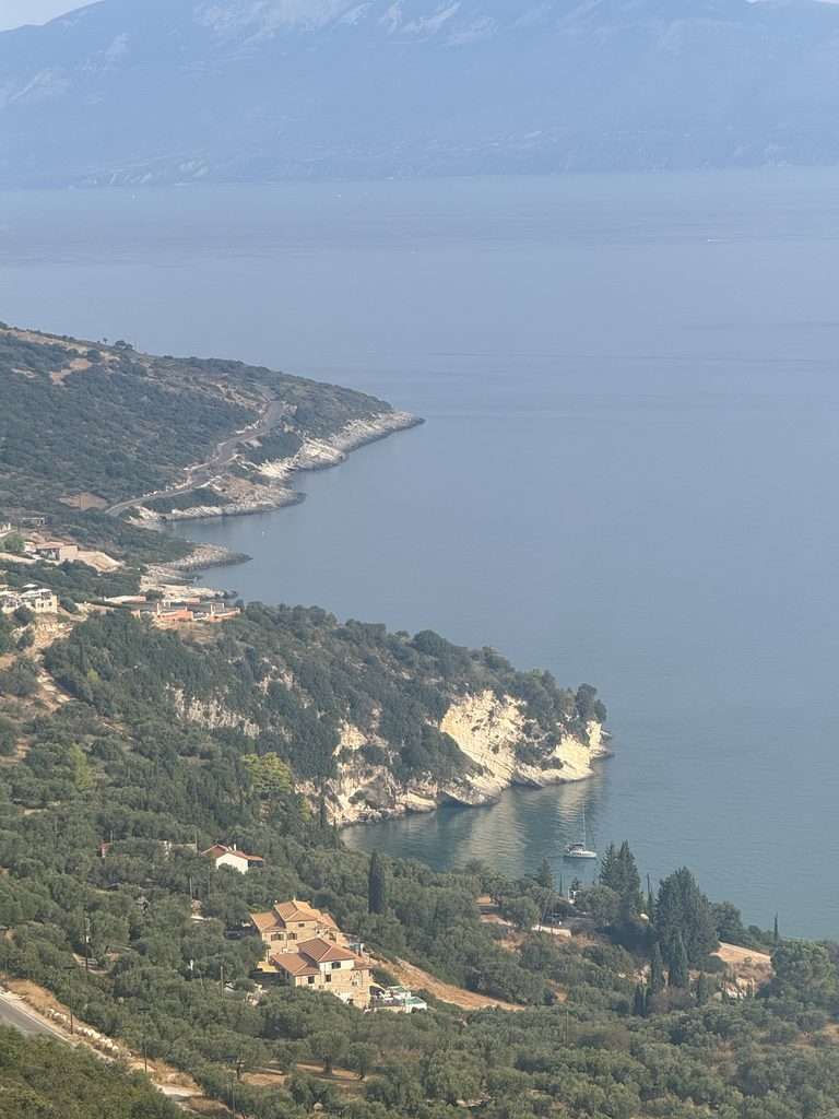 View of Zante’s coastline from Navagio viewpoint, with green hills, rocky cliffs and the blue sea.